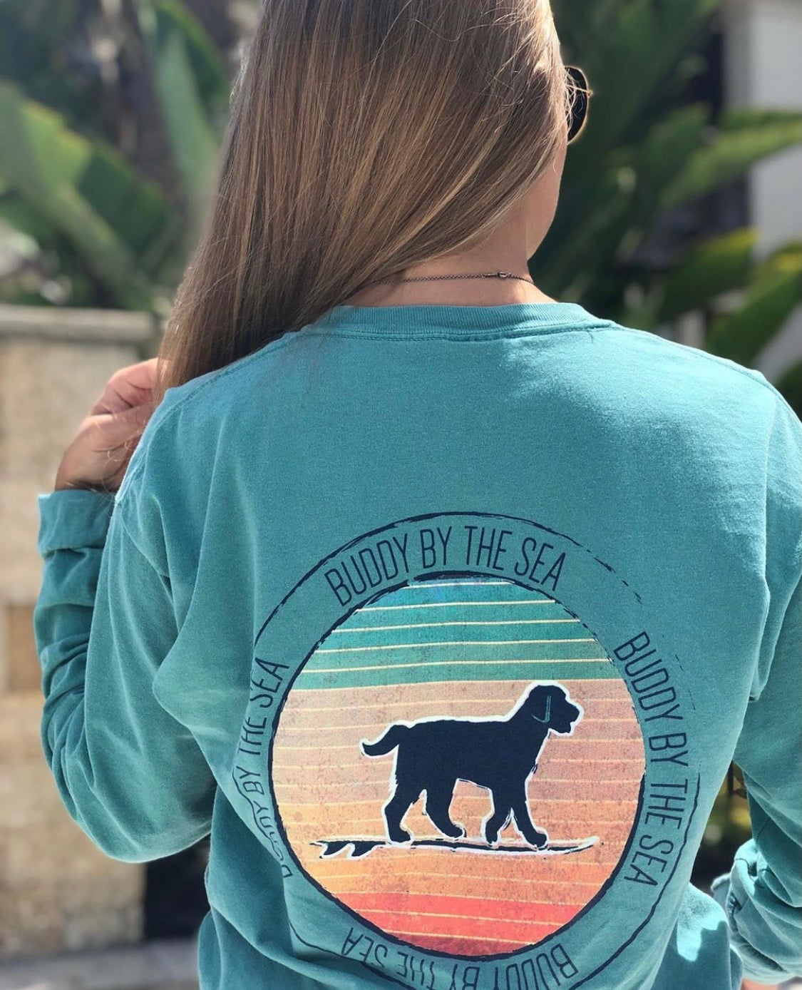 Woman wearing seafoam Buddy by the Sea long-sleeve comfort colors tee with surfing dog graphic