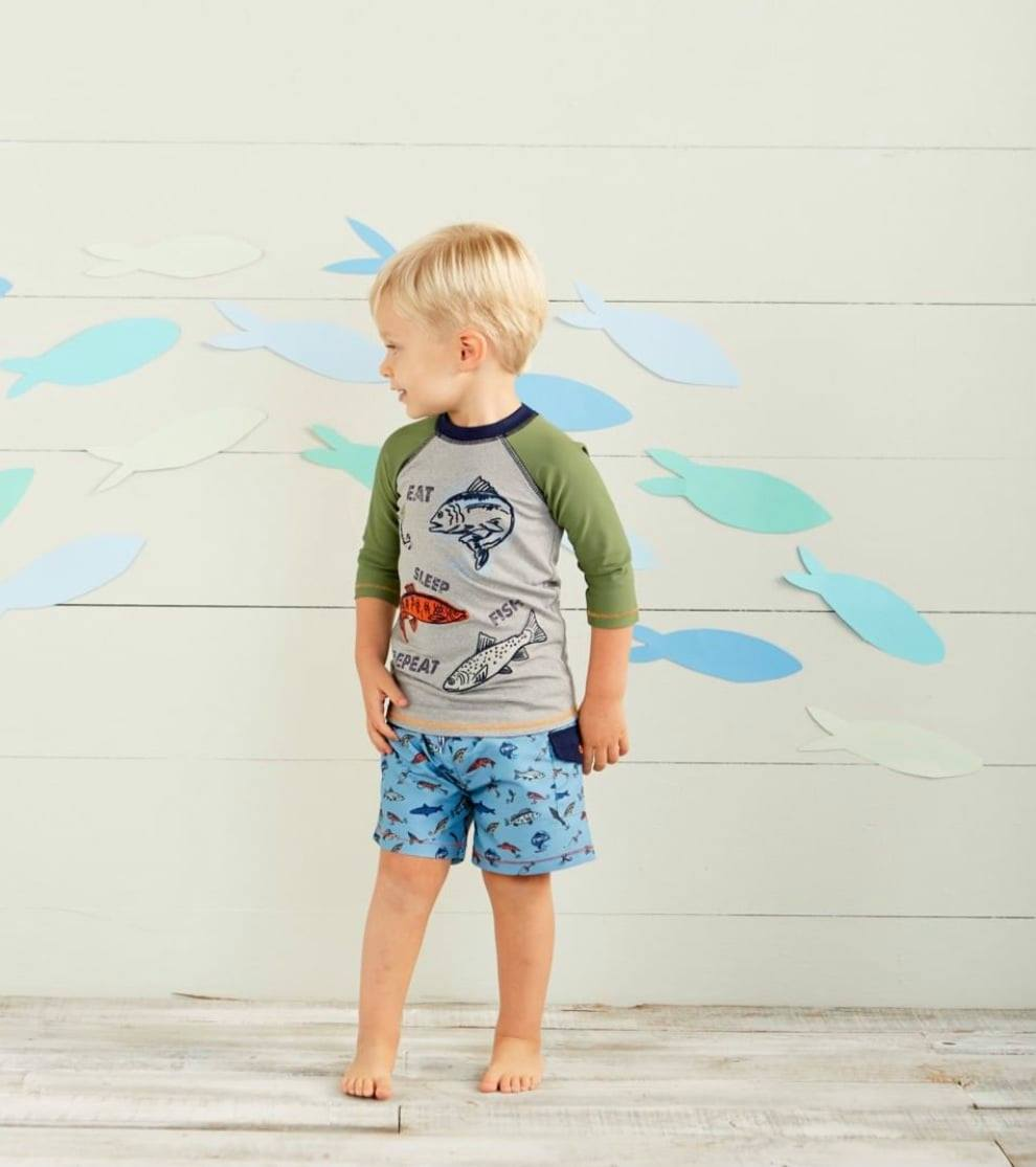 Little boy in fish print rashguard and swim shorts