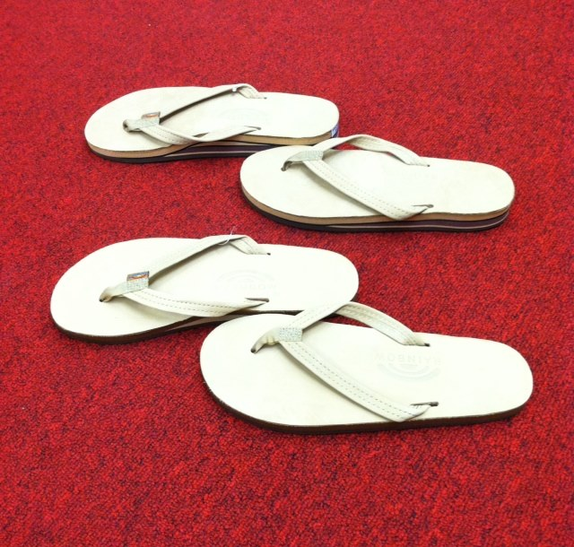 Southern Tide white women's flip flops displayed on red carpet