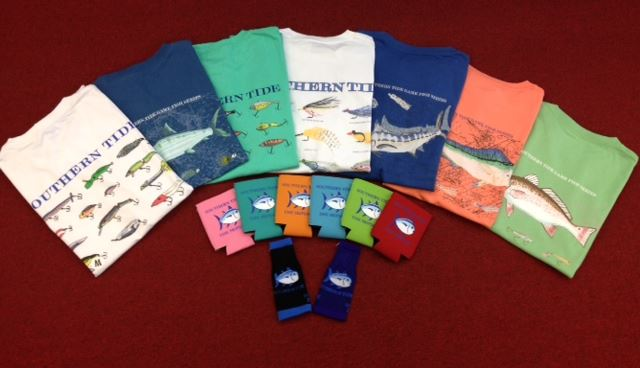 Southern Tide folded graphic tees in fish and lure prints fanned out on red carpet with colorful socks in the center
