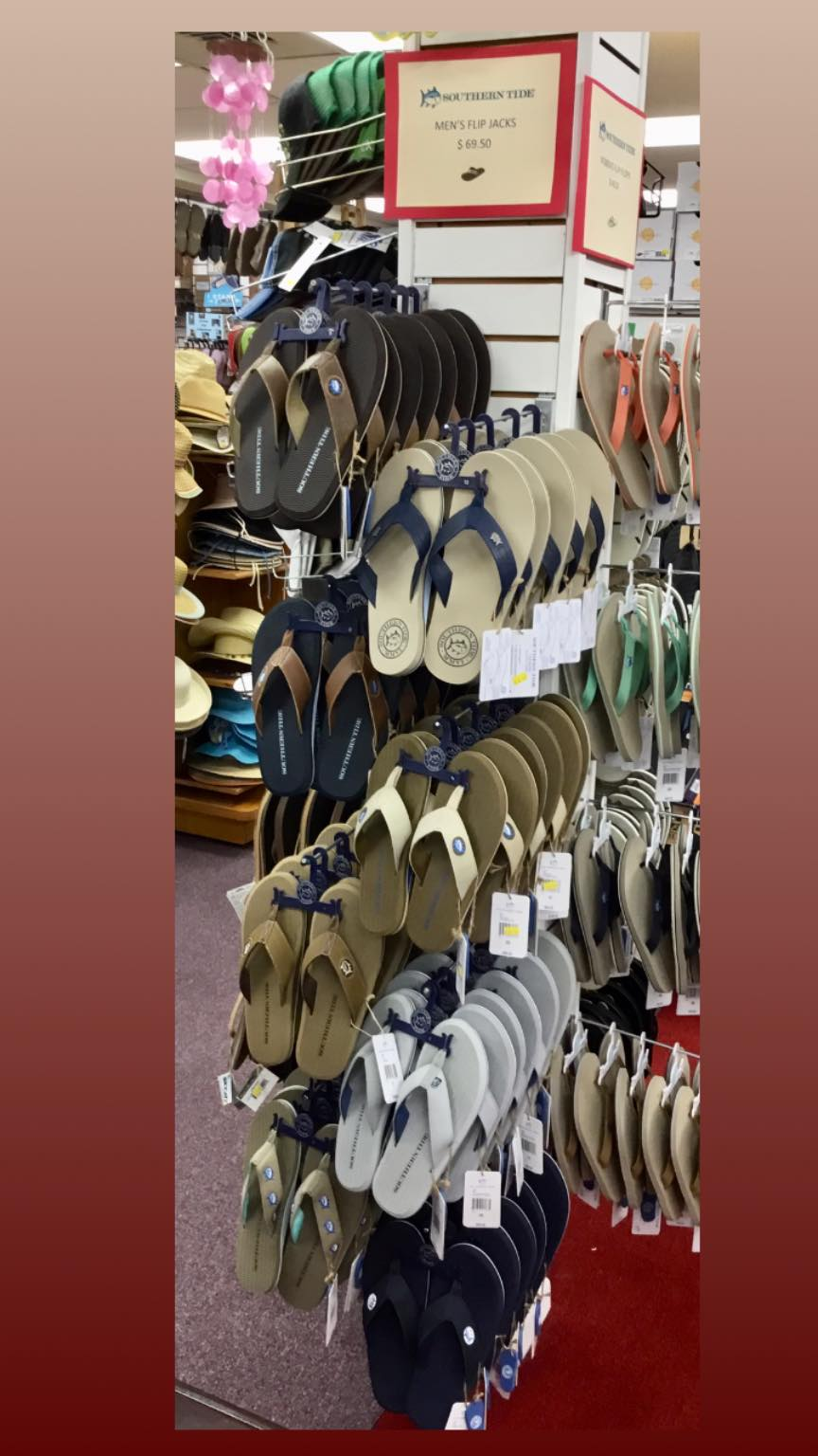 Wall display of Southern Tide men's Flip Jack sandals in tan, navy, brown and green colorways with red $69.50 sign