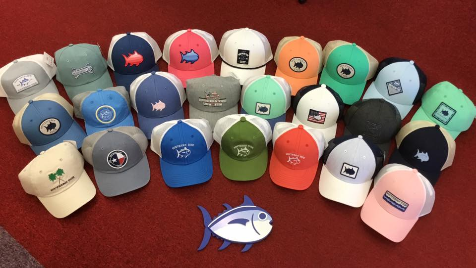 Two dozen Southern Tide Skipjack trucker caps arranged in a circle on red carpet around a blue Skipjack logo