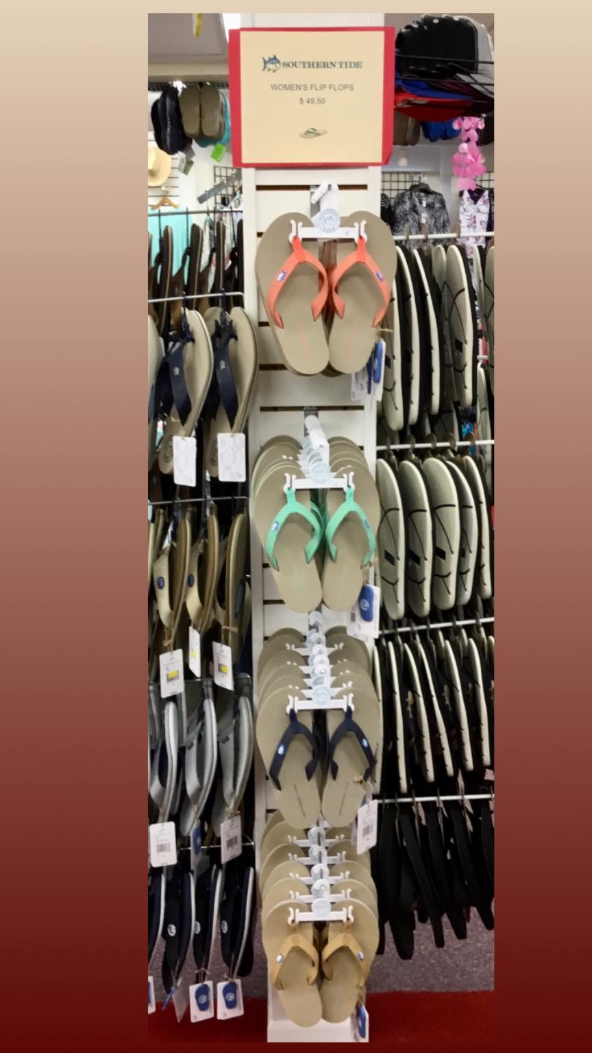 Tall display of Southern Tide women's flip flops in coral, mint, navy and tan with red $49.50 sign